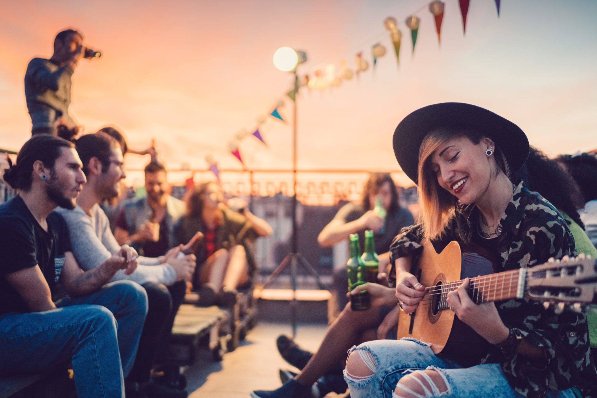Friends watching a woman play guitar on the rooftop